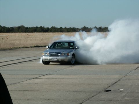 2001 Mercury Grand Marquis - A silver 2001 Mercury Grand Marquis performs a burnout, kicking up a large cloud of smoke.