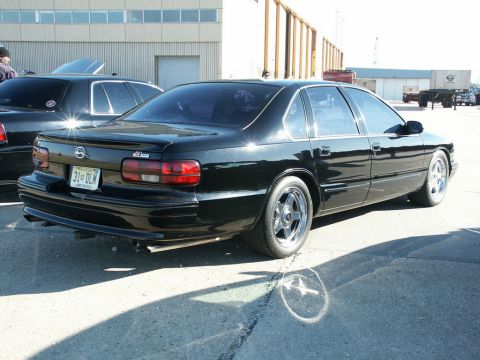2001 Mercury Grand Marquis - A black sedan with custom wheels is parked outdoors, with another car visible behind it.
