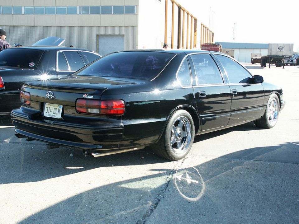 Black sedan rear view with custom wheels and a spoiler