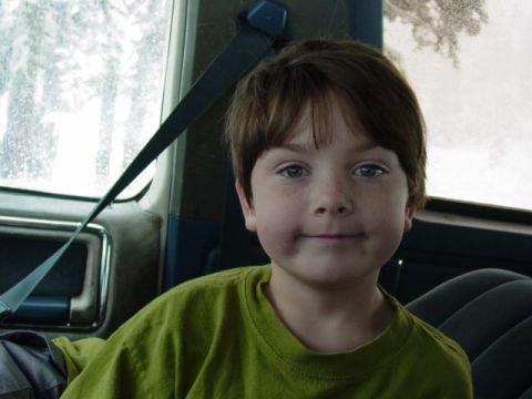 1986 Ford Bronco - A young child sits in the passenger seat of a vehicle, looking towards the camera.