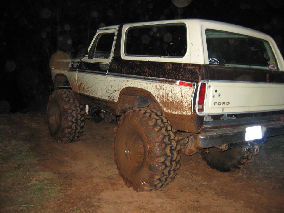 Mud-covered 1978 Ford Bronco, lifted with large tires, viewed from the rear