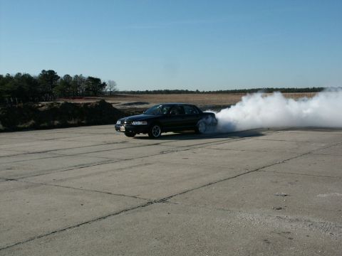 2001 Mercury Grand Marquis - A black sedan performs a burnout, creating a large cloud of smoke on a clear day.