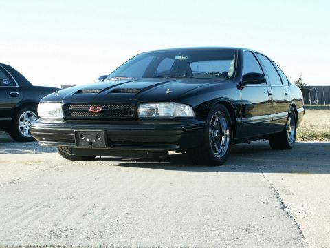 2001 Mercury Grand Marquis - A black Chevrolet sedan with a modified hood and aftermarket wheels is parked outdoors.