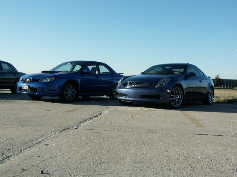 2001 Mercury Grand Marquis - Two blue coupes are parked on pavement under a clear blue sky.