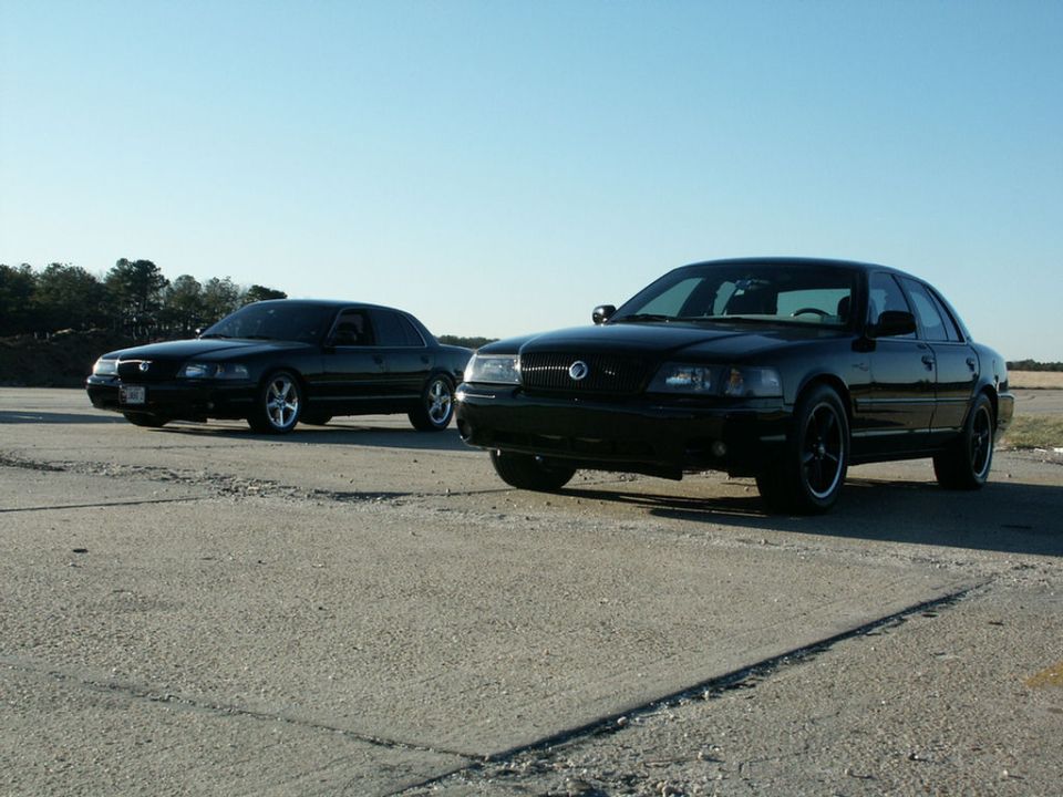 Two black 2001 Mercury Grand Marquis sedans parked on pavement