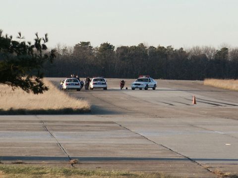 2001 Mercury Grand Marquis - Several police cars and a motorcycle are gathered on a paved surface, possibly a runway, with a traffic cone in the distance.