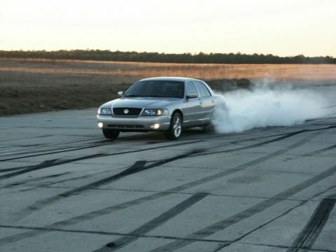 2001 Mercury Grand Marquis - A silver 2001 Mercury Grand Marquis drifts in a cloud of smoke on a paved surface with tire marks.
