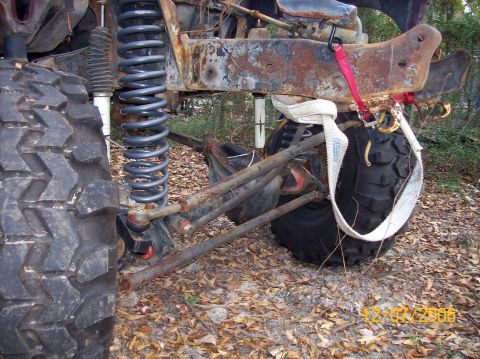1978 Ford Bronco - Close-up of heavily rusted vehicle frame and suspension components, with a large tire visible.