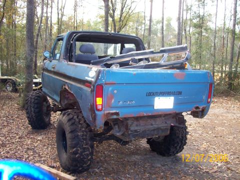 1978 Ford Bronco - This lifted 1978 Ford Bronco features off-road tires and a roll bar, seen in a wooded area.