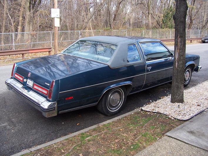 Dark blue 1977 Oldsmobile Delta 88 Royale coupe parked on a street, rear 3/4 view