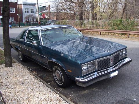 1999 Ford Crown Victoria - This 1977 Oldsmobile Cutlass Supreme coupe is parked curbside on a residential street.