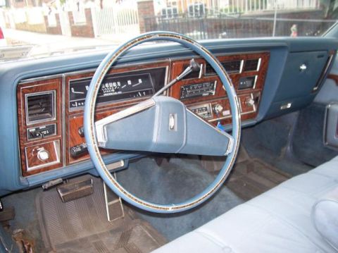 1999 Ford Crown Victoria - Interior view of a car's dashboard with a prominent steering wheel and wood trim accents.