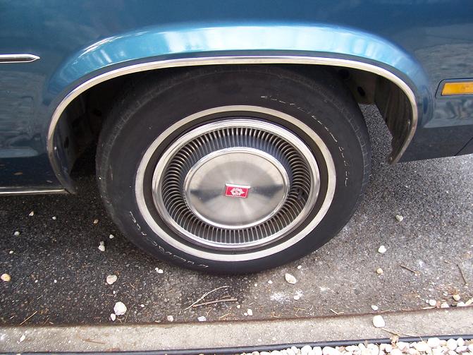 Close-up of a car's wheel with a chrome hubcap and whitewall tire