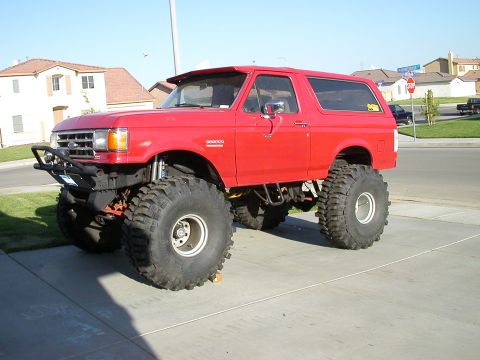 1991 Ford Bronco - Modified 1991 Ford Bronco with extreme lift and large tires parked on a driveway.