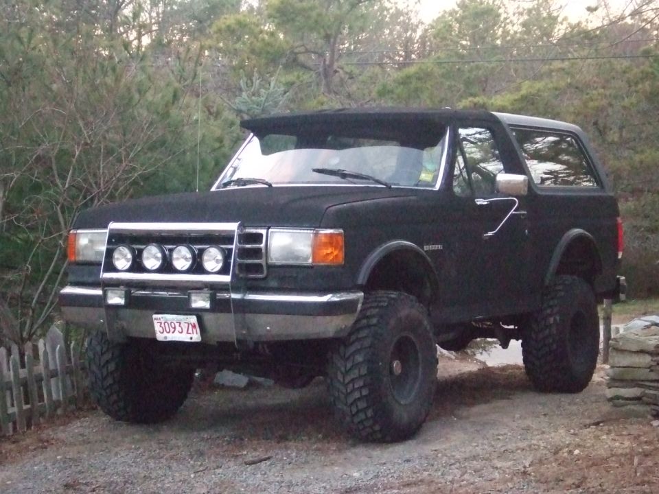 Black lifted 1987 Ford Bronco with aftermarket lights and large tires