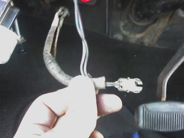 Hand holding a disconnected wiring harness connector inside a vehicle