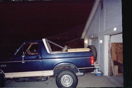 1990 Ford Bronco - This Ford Bronco is parked outside a garage with its rear facing the camera.