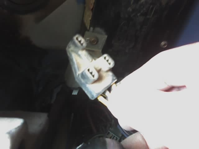 Hand holding a white electrical connector with three prongs
