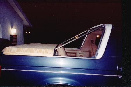 1990 Ford Bronco - The rear of a blue SUV is shown with a tan tonneau cover.