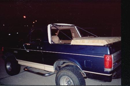 1990 Ford Bronco - Rear view of a blue and tan 1990 Ford Bronco, a soft tonneau cover over the cargo area.