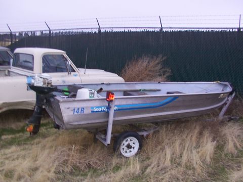 2003 Ford Ranger - An aluminum boat with a blue stripe is parked on a trailer next to a pickup truck.