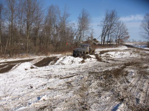 1979 Ford Bronco - A gray pickup truck navigates a challenging muddy and snowy terrain, with its body style suggesting a 1979 model year.