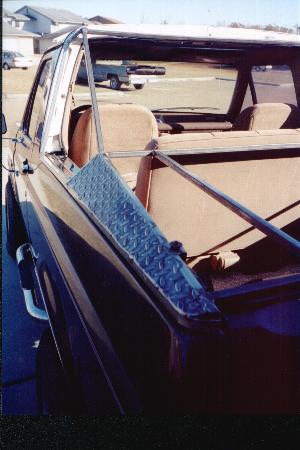 1990 Ford Bronco - The rear interior of a Ford Bronco shows tan seats and a metal divider in the cargo area.