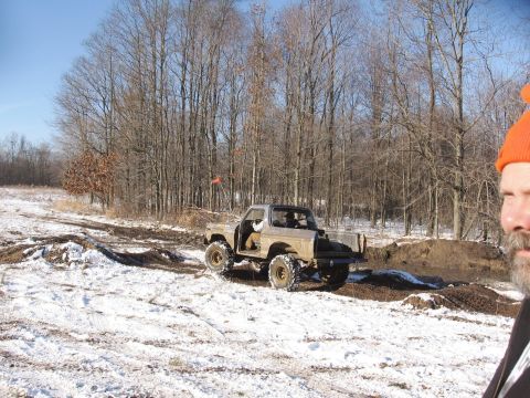 1979 Ford Bronco - A modified 1978 Ford Bronco navigates a muddy, snow-covered path through a forest.