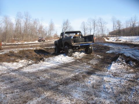 1979 Ford Bronco - A 1979 Ford Bronco navigates a challenging off-road course with mud and patches of snow.