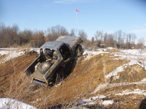 1979 Ford Bronco - Off-road vehicle attempts to climb a muddy incline on a cold, clear day.