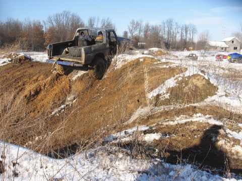 1979 Ford Bronco - This Ford Bronco is navigating a challenging muddy terrain with snow scattered across the landscape.