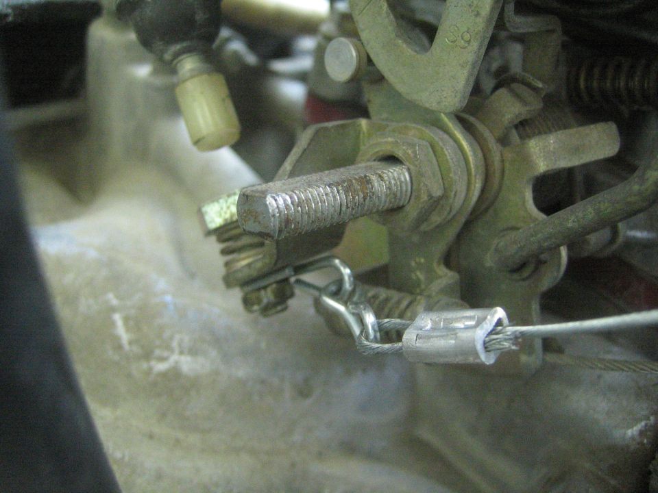 Close-up of a throttle linkage with a threaded bolt and cable clamp