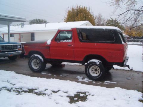 1978 Ford Bronco II - A red 1978 Ford Bronco II with a black top is parked outside in the snow.