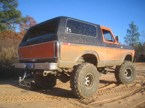 1979 Ford Bronco - This lifted 1979 Ford Bronco is shown in a rear 3/4 view, covered in mud from off-roading.