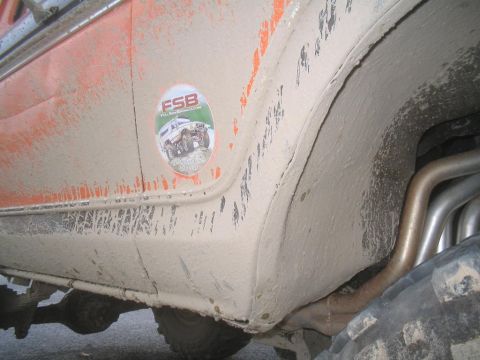 1979 Ford Bronco - A close-up view of a mud-covered vehicle's side panel, revealing a sticker with text and an image.
