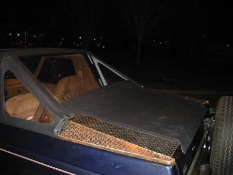 1990 Ford Bronco - 1990 Ford Bronco rear interior view, showing tan seats and a black tonneau cover with diamond plate trim.