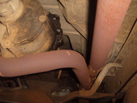 1988 Ford Bronco - Underside view of rusty exhaust pipes and a differential housing.