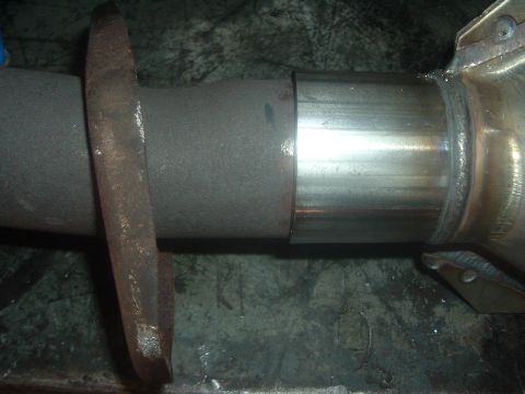 1989 Ford Escort - Close-up view of a vehicle's exhaust pipe connection, showing a flange and pipe joint.