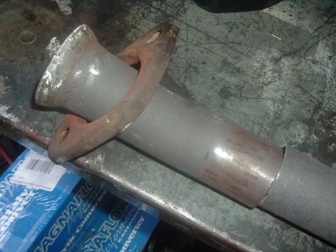 1989 Ford Escort - Close-up of an exhaust pipe section with a flange, alongside new catalytic converter packaging.