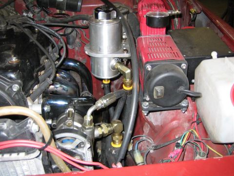 1987 Suzuki Samurai - Aftermarket air compressor installation in a vehicle's engine bay, with visible plumbing and electrical connections.