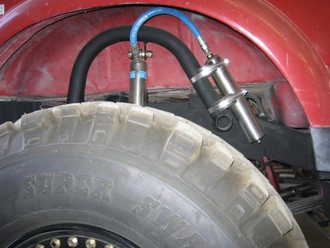 1987 Suzuki Samurai - Custom suspension parts visible near the rear tire of an off-road vehicle.