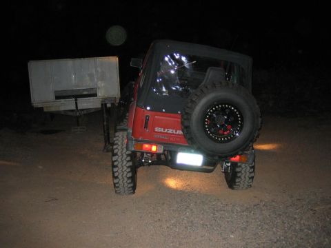 1987 Suzuki Samurai - The rear view of a red Suzuki Samurai is shown at night, hitched to a trailer.