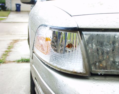 2000 Ford Crown Victoria - The front corner light and headlight assembly of a silver 2000 Ford Crown Victoria are visible, covered in water droplets.