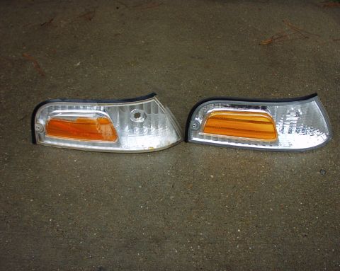 2000 Ford Crown Victoria - Two car corner lights are shown on a wet, concrete-like surface.