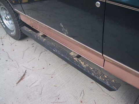 1995 Ford Bronco - Side view of a dark SUV, showing its running boards and copper-colored trim along the lower body.
