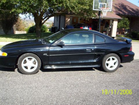 1995 Ford Mustang - Side profile of a black 1995 Ford Mustang coupe parked in a suburban driveway.