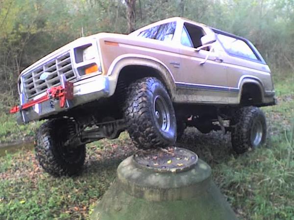 Lifted tan Ford Bronco SUV with large mud tires and front winch outdoors