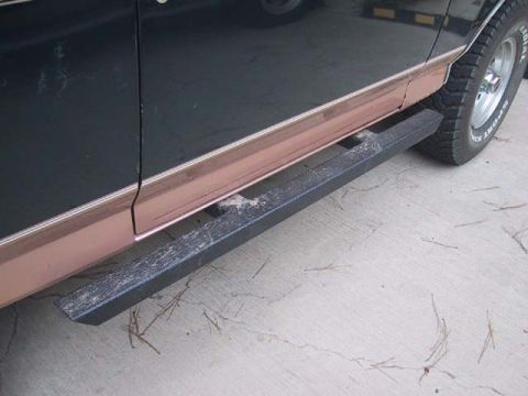 1995 Ford Bronco - Aftermarket rock sliders are installed on the side of a dark-colored SUV.