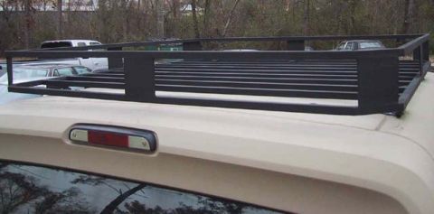 1995 Ford Bronco - A black roof rack is mounted on the top of a tan vehicle, with other vehicles visible in the background.