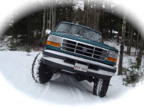 1996 Ford Bronco - A green 1996 Ford Bronco navigates a snowy, wooded area.